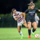 Grace Coppinger (23) tussles with an Aggie defender for the ball.